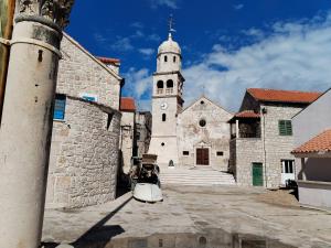a church with a clock tower in a city at Ema in Prvić Šepurine +14 photos