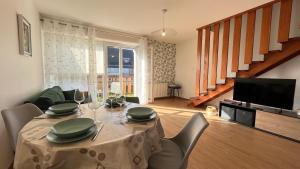 a dining room with a table with chairs and a television at Appartement les Capucins ROSCOFF in Roscoff