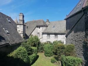 an old stone building with bushes and trees at Le Lys bleu in Salers