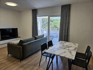 a living room with a couch and a table with chairs at Apartmani Rafaella in Lopar