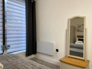 a bedroom with a mirror and a bed and a window at Town Centre Two-Bedroom in Swindon