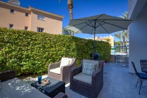 a patio with two chairs and an umbrella at Iris Bloom Holiday Apartment in Paphos City