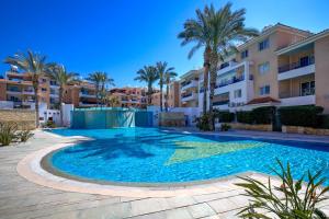 a large swimming pool with palm trees and buildings at Iris Bloom Holiday Apartment in Paphos City