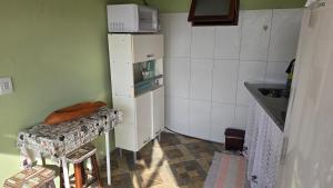 Una pequeña cocina con una mesa y un refrigerador. en Suite Pássaros, en Ilhabela