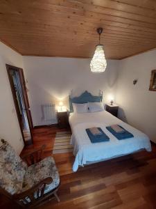 ein Schlafzimmer mit einem großen Bett und einem Stuhl in der Unterkunft Casa da Laura - Um refúgio na Serra da Estrela in Alvoco da Serra