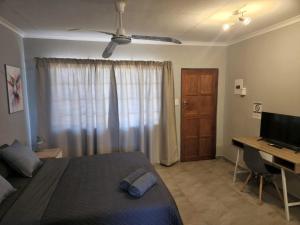 a bedroom with a bed and a desk and a television at Zondereinde Accommodation in Wag ʼn Bietjie Draai