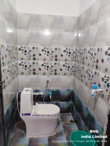 a small bathroom with a toilet and flowers on the wall at प्रभु श्रीराम नगरी गेस्ट हाउस in Ayodhya +18 photos