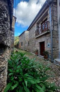 ein altes Steingebäude mit einem Balkon und einer Pflanze in der Unterkunft Casa da Laura - Um refúgio na Serra da Estrela in Alvoco da Serra + 47 Fotos