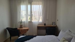 a bedroom with a bed and a desk and a window at Private room in a shared apartment with pool in Agadir