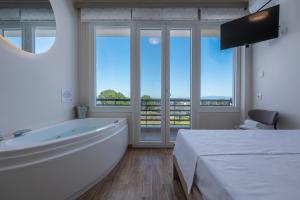 a bathroom with a tub and a bed and windows at Dream Suites in Vourvourou