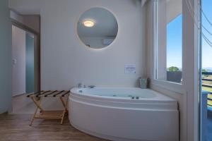a white bathroom with a tub and a round mirror at Dream Suites in Vourvourou +21 photos