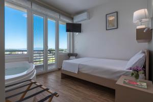 a bedroom with a tub and a bed and a balcony at Dream Suites in Vourvourou