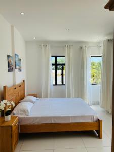 a bedroom with a large bed and two windows at Flic en Flac Luxe Seascape in Flic-en-Flac