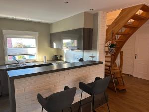 a kitchen with a counter with chairs and a staircase at Raelax in Raeren