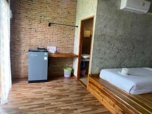 a room with a bed and a brick wall at The Nanda Resort in Ban Huai Salok