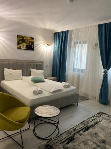 a bedroom with a bed and a chair and a window at Hotel Green House in Craiova
