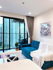 Long BìnhShi House - 1BR Building S1003 Swimming Pool View的客厅里有一张蓝色的沙发和一扇大窗户