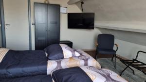 a bedroom with a bed and a tv and a chair at MARINA in Aan de Wolfsberg