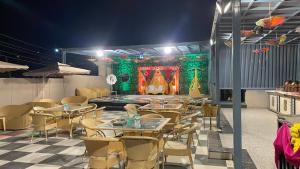 a restaurant with tables and chairs and a stage at THE ROYAL Inn in Faridabad +3 photos