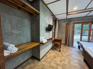 a room with a bed and a desk and a television at The Nanda Resort in Ban Huai Salok