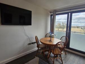 a dining room table with chairs and a large window at Slough Luxhaven Elegant One-Bed Apartment on High Street in Slough