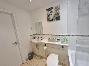 a bathroom with a toilet and a sink and a shower at Slough Luxhaven Elegant One-Bed Apartment on High Street in Slough +14 photos