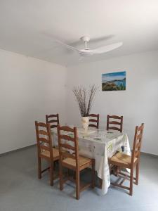 Una mesa de comedor con sillas y un ventilador de techo. en Belle location vue sur mer, en Deshaies