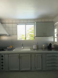 a kitchen with white cabinets and a sink at Belle location vue sur mer in Deshaies +14 photos