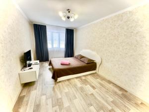 a bedroom with a bed and a desk and a television at Квартира 43 in Karagandy