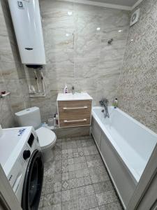 a bathroom with a toilet and a sink and a washing machine at Квартира 43 in Karagandy