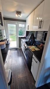 a kitchen with white cabinets and a black counter top at Ranger - Snowdon Cabins holiday let Caernarfon in Caeathro