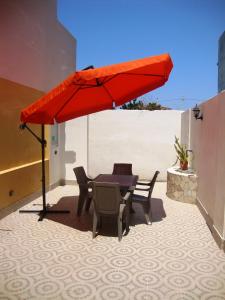 a red umbrella on a patio with a table and chairs at Casa Vacanze Spadafora in Spadafora