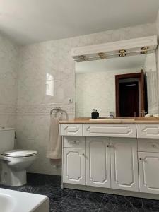 a bathroom with a toilet and a sink and a mirror at Magnifico ático con vistas, parking y piscina in Puigcerdà