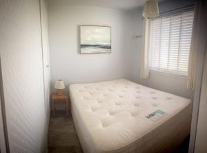 a bed in a room with a window at Norfolk Beach Chalet - California Sands Resort in Great Yarmouth +2 photos