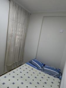 Schlafzimmer mit einem Bett mit einem Fenster und einem Kissen in der Unterkunft Mini departamento acogedor en el centro de Huánuco in Huánuco + 3 Fotos