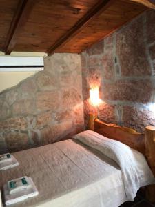 ein Schlafzimmer mit einem Bett in einer Steinmauer in der Unterkunft Cabañas La Cautiva in Tanti