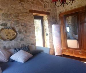 a bedroom with a blue bed and a stone wall at Climb and dive South ! in Kapetanianá +39 photos