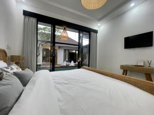 Un dormitorio con una cama blanca y una ventana grande. en Villa Loli Sanur, en Sanur