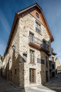 a stone building with windows and a balcony at Casa Natal del Gigante de Sallent in Sallent de Gállego