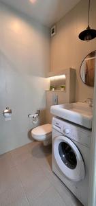 a bathroom with a washing machine and a toilet at Комфортная студия в Золотом квадрате гАлматы in Almaty