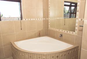 a bath tub in a bathroom with a mirror at Lalapanzi Guest Lodge in Gqeberha +13 photos