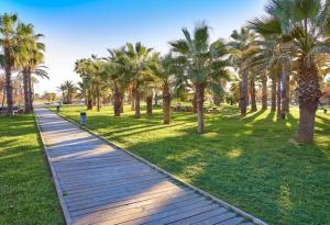 a wooden path in a park with palm trees at Playa del Pinar home in Grao de Castellón