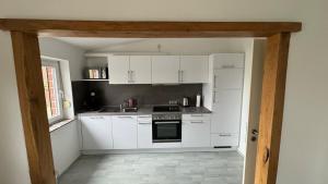 a kitchen with white cabinets and a stove top oven at Moderne Industriewohnung in Everswinkel
