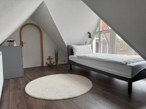a bedroom with a bed and a white rug at Das Atelier in Krummhörn