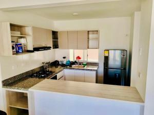 a kitchen with white cabinets and a black refrigerator at Ciudad Cristales in Villeta