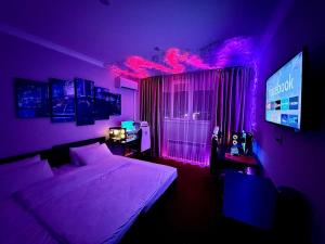 a bedroom with a purple room with a bed and a monitor at Harmony Inn in Almaty