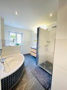 a bathroom with a tub and a glass shower at The Villa Toscana, a serene retreat in Center of Friedrichshafen City with lush green lawns, terrace & private garage- Lidl, Bakery walking distance- Bodenseecenter, Sportsbad 3 mins, Lake 7 mins in Friedrichshafen