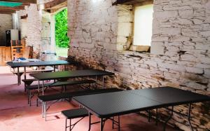 a row of tables in a room with a brick wall at Camping Vieilles Charrues Petit-déjeuner navette et priscine inclus dans le prix proche Carhaix in Motreff
