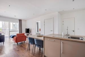 a kitchen with a sink and a counter with chairs at Modern, Spacious 2bed, 2bath apartment in Barking in Barking