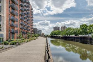 a canal in a city with tall buildings and water at Modern, Spacious 2bed, 2bath apartment in Barking in Barking
